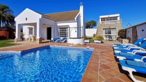 A swimming pool with lounge chairs, a white building with a tiled roof, and a stone tower. - Casa Zahora - extended families' first choice! (Cádiz)