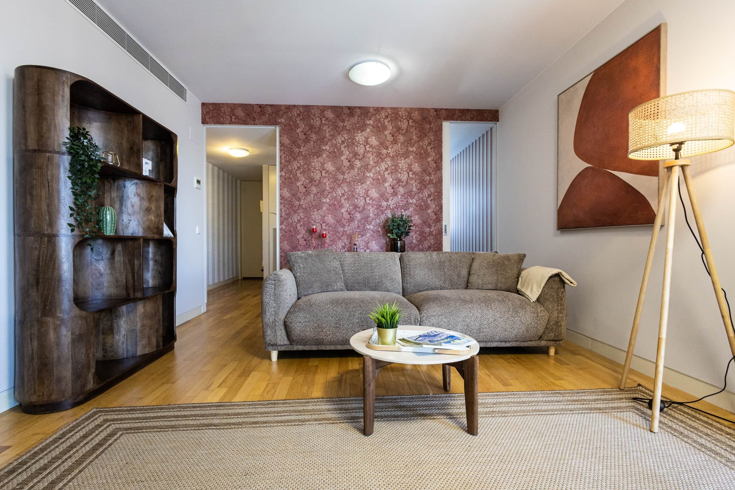 Een zithoek met een bank, salontafel, vloerlamp en decoratieve wandversiering.