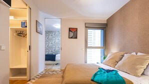 Un dormitorio con cama, armario, ventana y puerta que conduce a otra habitación.