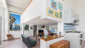 A spacious living area with a sofa, a wooden bench, and a kitchen with a stove and cabinets.