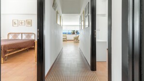 A narrow hallway with a bed on the left and a kitchen area at the end.