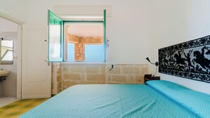 Ein Schlafzimmer mit Bett, Fenster, Badezimmer und einer Wand mit einem Zierpaneel.