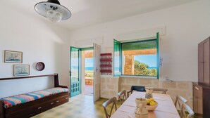 Ein Zimmer mit einem Bett, einem Esstisch mit Stühlen, einer Vase und einer Obstschale.