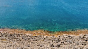 Eine Küstenlandschaft mit klarem, blauem Wasser und felsigem Gelände.