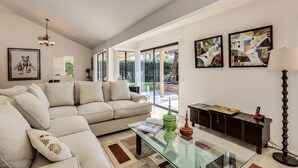 Ein modernes Wohnzimmer mit einem beigefarbenen Sofa, einem Glastisch und abstrakter Kunst an den Wänden.