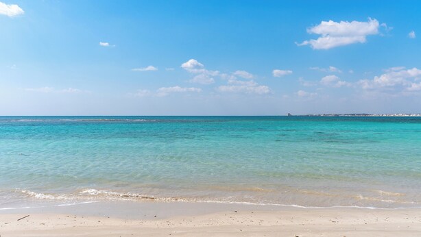 Ein Strand mit klarem türkisblauem Wasser und sandigem Ufer.