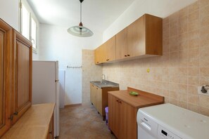 A compact kitchen with wooden cabinets, a built-in sink, and a dishwasher. - Villa Jole - Bilocale by BarbarHouse (Torre Suda)