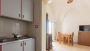 A kitchen with a double sink, a stove, and a dining area with a table and chairs. - Villa Jole - Trilocale by BarbarHouse (Torre Suda)