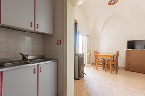 A kitchen with a double sink, a stove, and a dining area with a table and chairs.