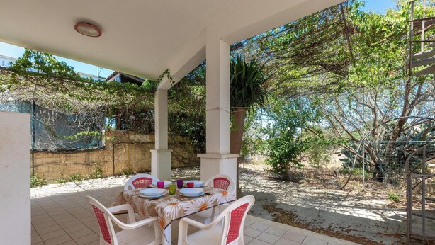 A covered patio with a table set for four, surrounded by white plastic chairs. - Villa Jole - Trilocale by BarbarHouse (Torre Suda)
