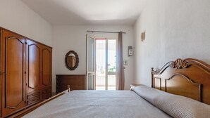 A bedroom with a large bed, wooden wardrobe, and a door leading to an outdoor area. - Villa Jole - Trilocale by BarbarHouse (Torre Suda)