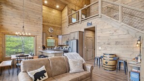 Un intérieur de chalet chaleureux, avec un revêtement mural en bois, un coin repas, une cuisine et un escalier.