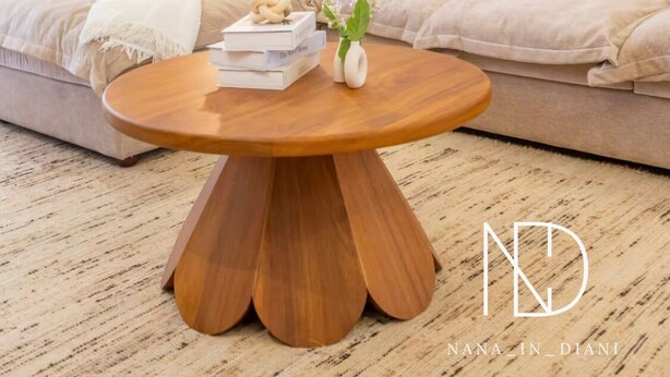 Un salon moderne avec un canapé beige, une table basse ronde en bois et deux reproductions botaniques encadrées accrochées au mur.
