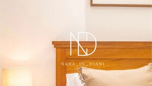 Un lit bien fait, avec une tête de lit en bois, une lampe de chevet et une prise électrique fixée au mur.
