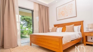 Une chambre à coucher avec un lit en bois, des rideaux beiges, une grande fenêtre et une œuvre d’art encadrée accrochée au mur.