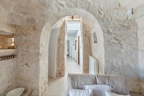 Ein Flur mit Stehwänden, der zu einem Zimmer mit einem Bett und einem kleinen Tisch führt.