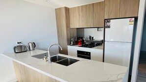 Une cuisine moderne dotée d’un îlot central, d’appareils électroménagers en acier inoxydable et de meubles de rangement en bois.