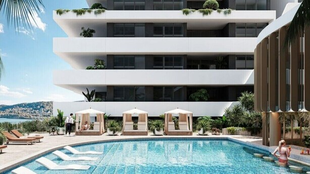 Un hôtel moderne doté d’une piscine, de chaises longues et offrant une vue sur la mer.
