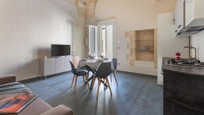 Een moderne keuken met een gasfornuis, een eethoek met een tafel en stoelen, en een televisie op een kast.