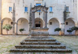 A courtyard with a central staircase leading to an entrance, surrounded by arches and a building facade. - Sternatia Loft by BarbarHouse (Sternatia)