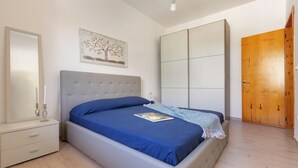 A bedroom with a bed, a nightstand, a dresser, a wardrobe, and a door. - Villino Pascoli by BarbarHouse (Torre dell'Orso)