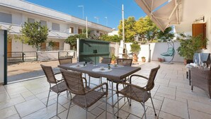 A patio area with a table and chairs, surrounded by potted plants and a green fence. - Villino Pascoli by BarbarHouse (Torre dell'Orso)