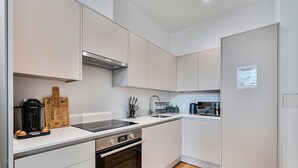 A modern kitchen with a built-in oven, a coffee machine, and a kettle. - 2-Bed Staines Stay | Parking | Heathrow & London Access (Staines-upon-Thames)