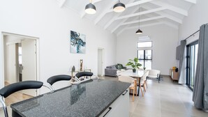 A modern kitchen with a granite countertop, black bar stools, and pendant lighting. - Modern 2-Bedroom Home in Langebaan, Solar Power, Braai & Near Beach (Langebaan)