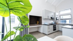 A modern kitchen with white cabinets, a brick backsplash, and a window. - Modern 2-Bedroom Home in Langebaan, Solar Power, Braai & Near Beach (Langebaan)