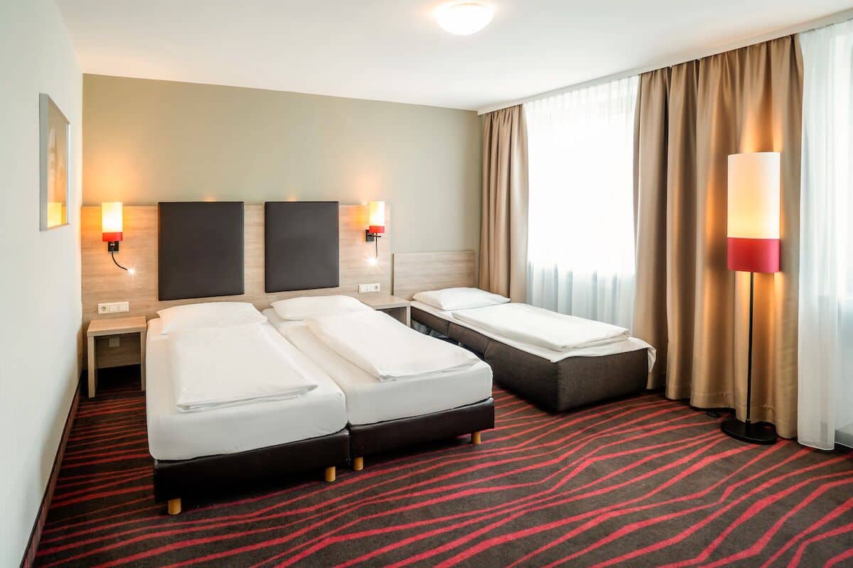 Ein Hotelzimmer mit zwei Betten, einem roten Teppich und zwei Wandlampen.