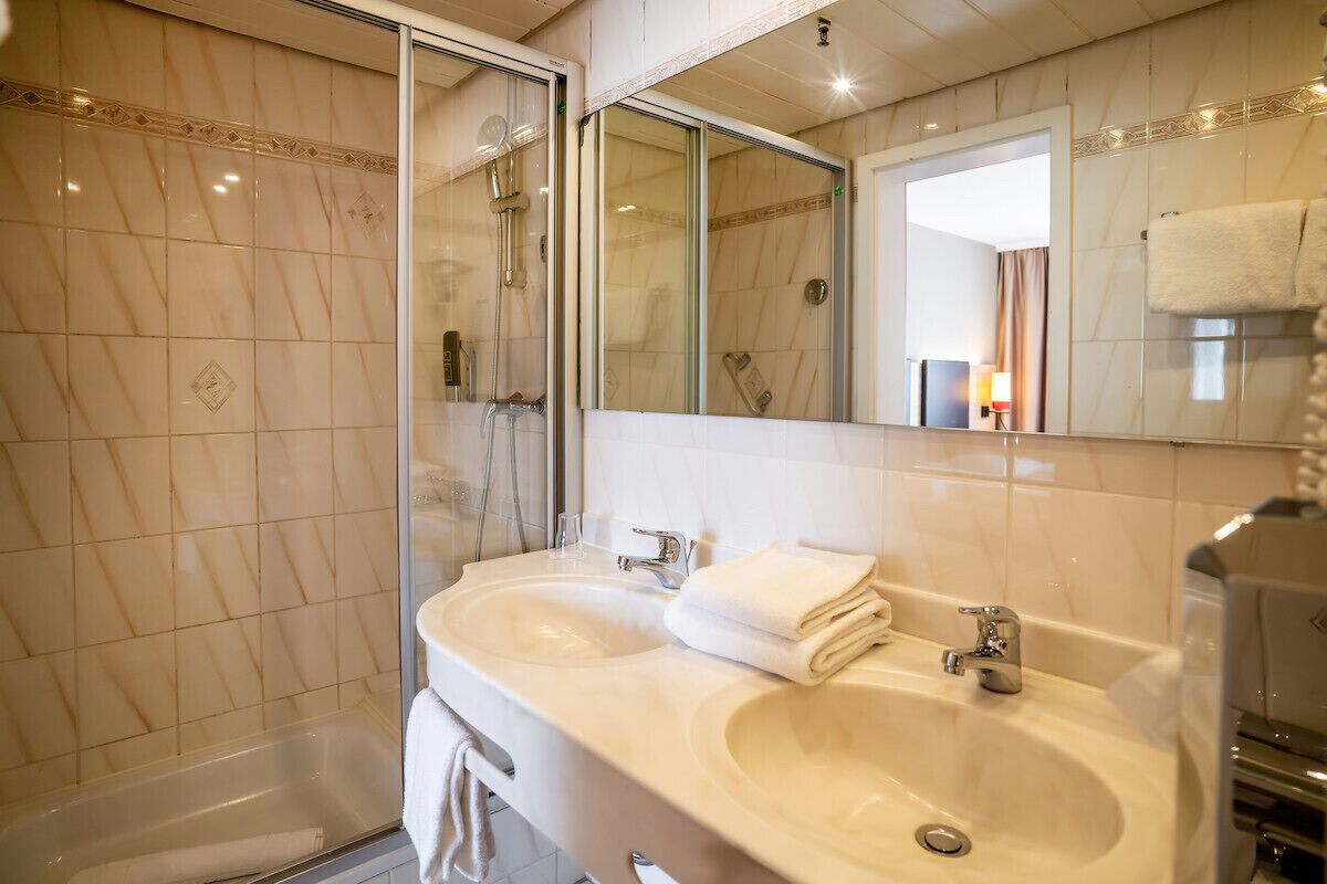 A bathroom with two sinks, a glass shower enclosure, and a large mirror.
