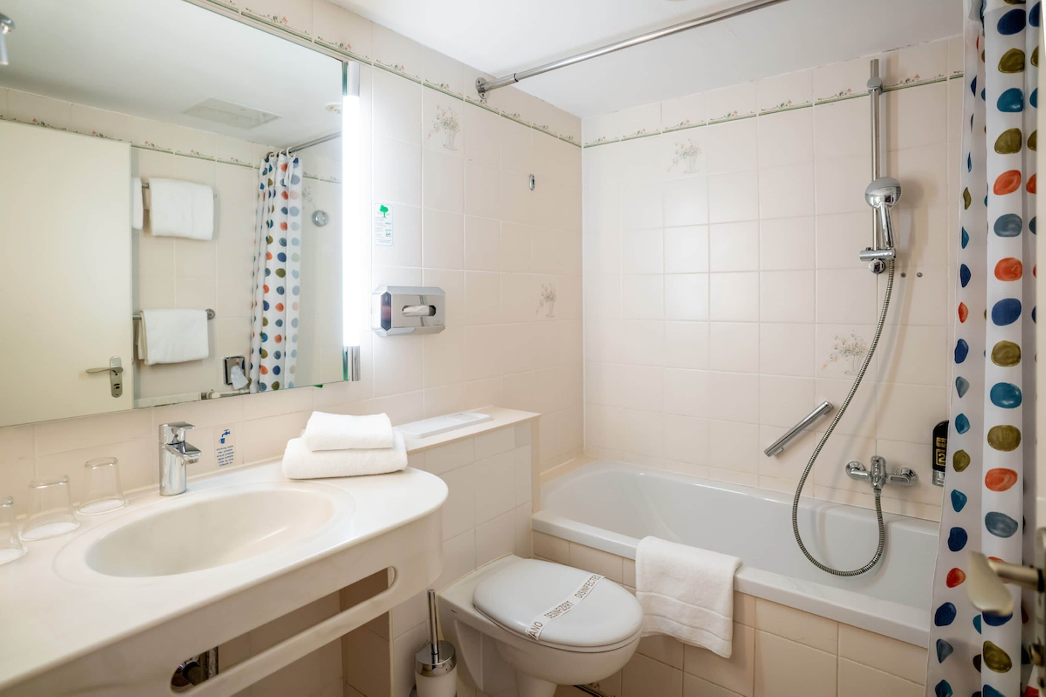 A bathroom with a bathtub, toilet, sink, and a mirror.