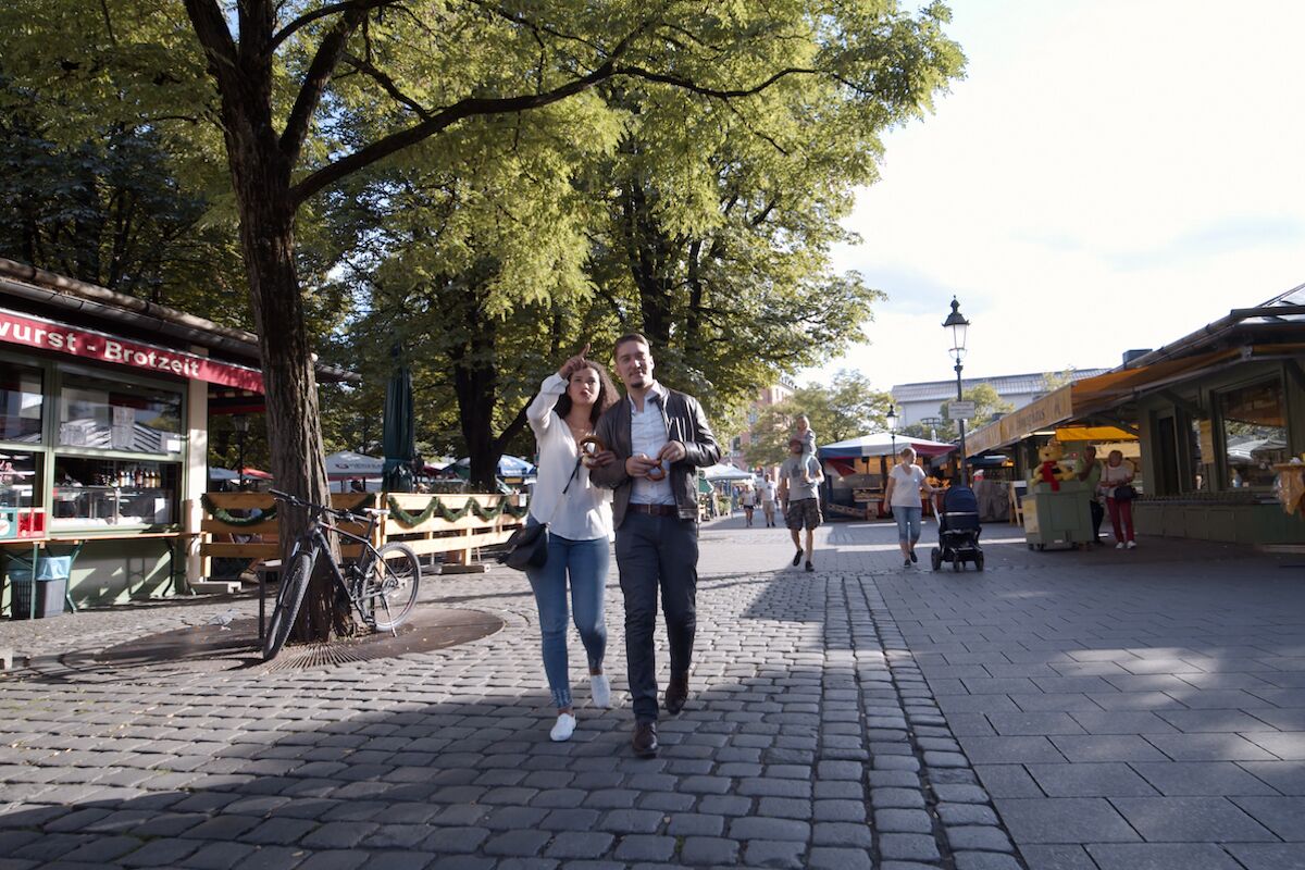 A cobblestone street with a café on the left and a market stall on the right.