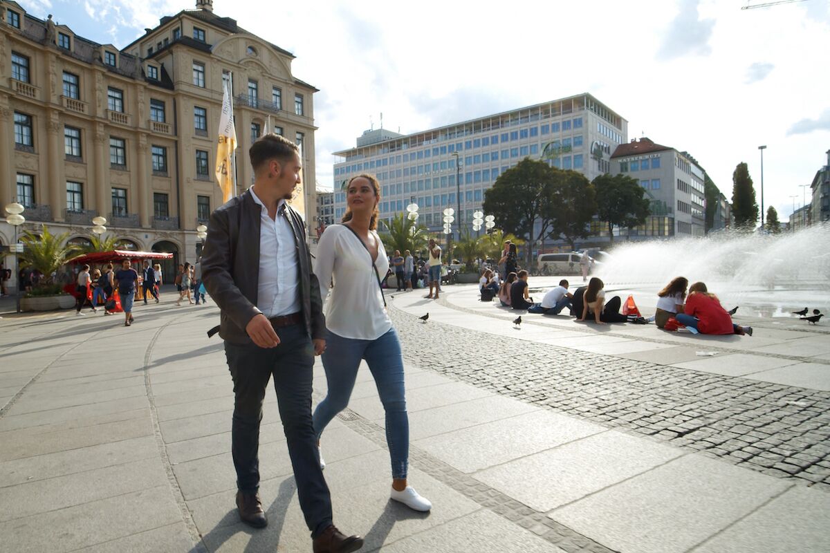 A public square with a fountain, people sitting and walking around.