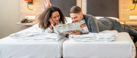 Una habitación de hotel con una cama, una mesita de noche y una lámpara de pared.