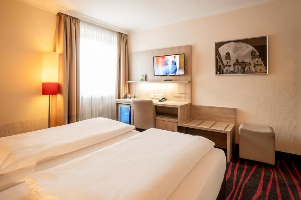 A hotel room with two beds, a desk, a TV, and a picture on the wall.