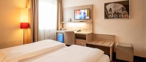 A hotel room with two beds, a desk, a TV, and a picture on the wall.
