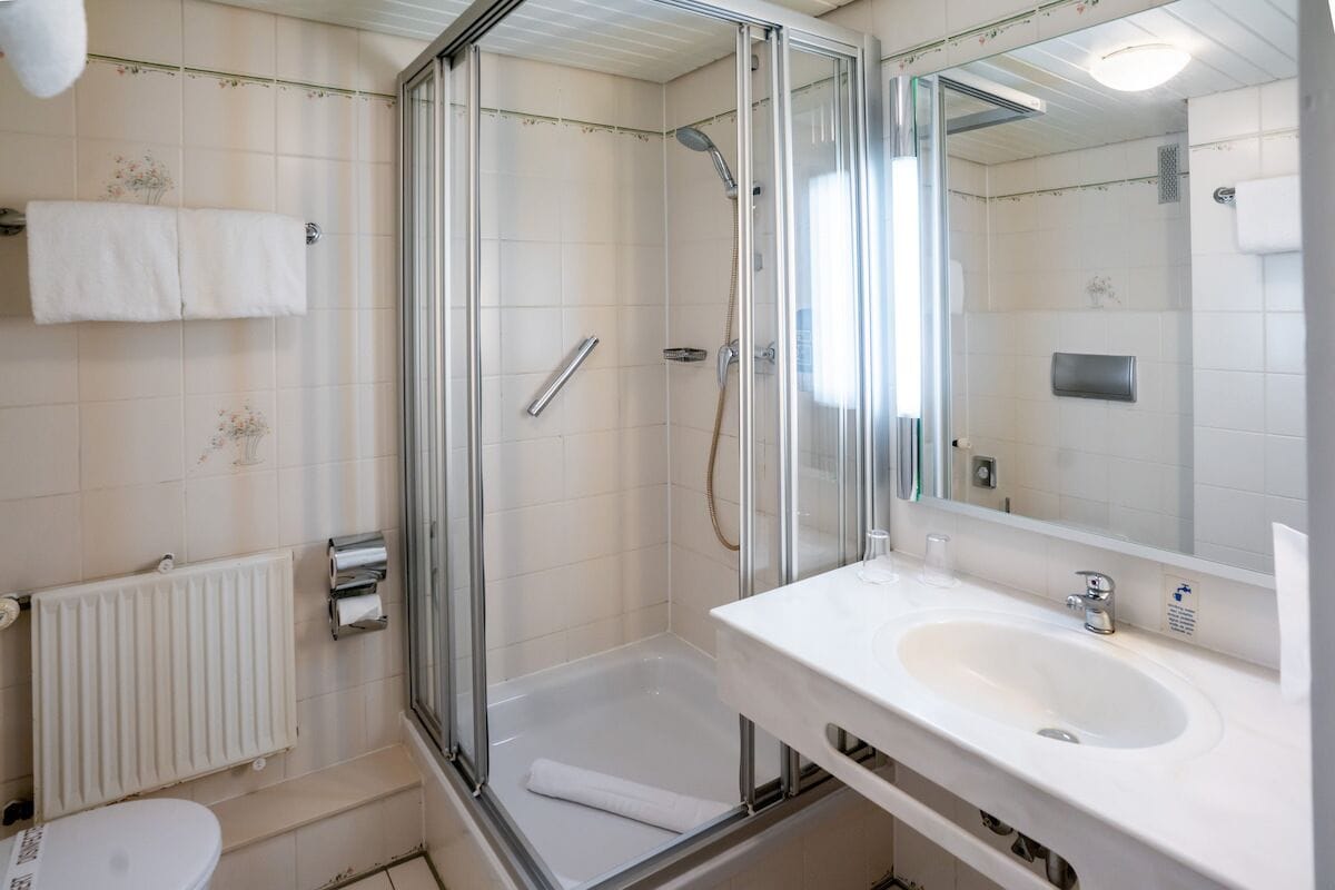 A bathroom with a glass-enclosed shower, a white sink, and a toilet.