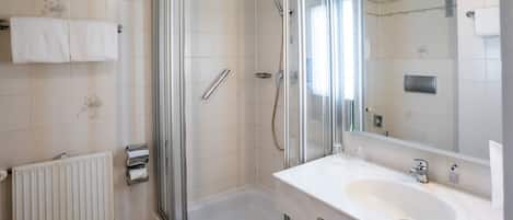 A bathroom with a glass-enclosed shower, a white sink, and a toilet.