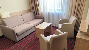 A hotel room with a sofa, two armchairs, a coffee table, and a lamp. - Hotel Europäischer Hof  (Munich)