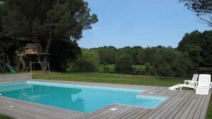 Ein rechteckiger Swimmingpool mit einer ihn umgebenden Holzterrasse.