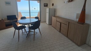 A compact living space with a dining area, kitchenette, and a large window offering a view of the sea. - 3-room seafront apartment, terrace, pets allowed, parking (Argelès-sur-Mer)