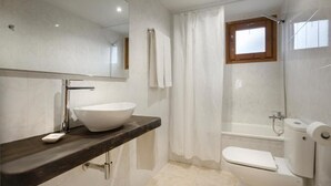 A bathroom with a large mirror, a white sink, a bathtub, and a toilet. - Hostal Kimboa (Ansó)