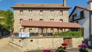 A stone building with a sign indicating it is a hostel. - Hostal Kimboa (Ansó)