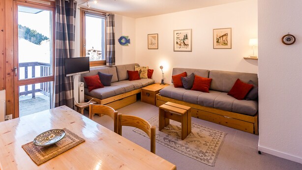 A cozy living room with a sofa set, a dining table, and a TV. - 2-room apartment near slopes - 5 people (La Plagne Montchavin Les Coches)