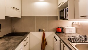 A modern kitchen with white cabinets, a microwave, a kettle, and a bread maker on the counter. - 2-room apartment near slopes - 5 people (La Plagne Montchavin Les Coches)