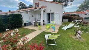 A white house with a tiled roof, a patio with green chairs, and a windmill. - Holiday home with pool, close to beach - La Tranche-sur-Mer (La Tranche-sur-Mer)