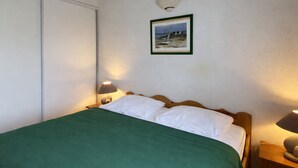 A bedroom with a bed, two bedside lamps, a framed picture on the wall, and a green bedspread. - Holiday home with pool, close to beach - La Tranche-sur-Mer (La Tranche-sur-Mer)
