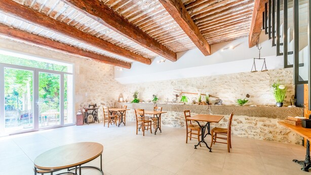 Un comedor amplio con mesas y sillas de madera, una pared de piedra y un ventanal con vistas a zonas verdes.