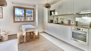 A modern kitchen with white cabinets, a wooden countertop, and a built-in oven. - Charming T2 with cabin 50m from slopes for 4-5 pers (Les Gets)